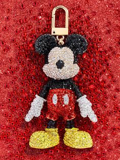 a mickey mouse keychain is shown on a red glittered surface with the word disney written in it