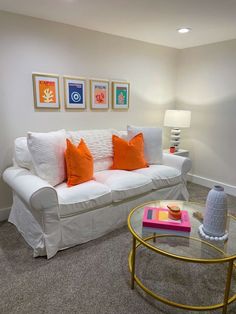 a living room with white couches and orange pillows