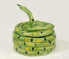 a green snake statue sitting on top of a stack of coils in front of a white background