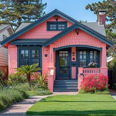 a pink house with blue trim and black shutters on the front door is shown