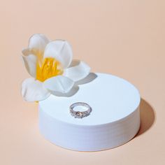 a ring sits on top of a white box with a flower in the middle,