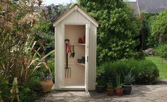 a garden shed with gardening utensils in the door and potted plants outside