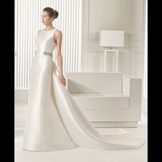 a woman in a white wedding dress standing next to a couch