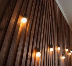 the lights are hanging on the wooden wall