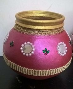 a pink vase with gold trim and flowers on it's side sitting on a table