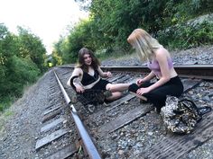 two women sitting on train tracks next to each other