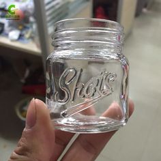 a person holding a glass jar with the word shoe on it