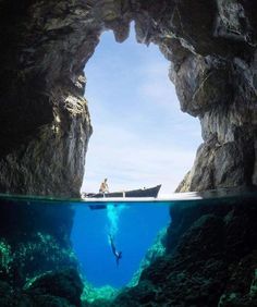 a person swimming in the water near a cave