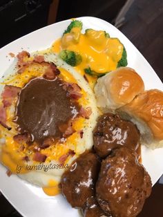 a white plate topped with meatballs covered in gravy next to potatoes and broccoli