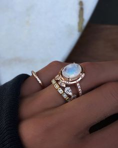 a woman's hand holding a ring with an opal and diamonds on it