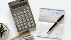 a calculator, pen and money on a desk