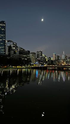 the city is lit up at night and reflecting in the water with its lights on