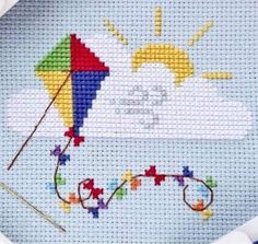 a cross - stitch picture of a kite on a blue sky with clouds and sun