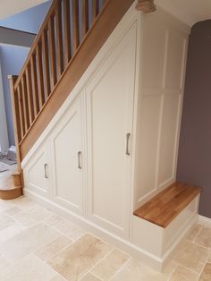 an empty room with white cupboards under the stairs and wooden bannisters on either side