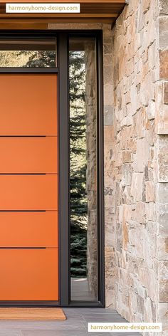 an orange front door on a stone building with glass panels and wood trimmings