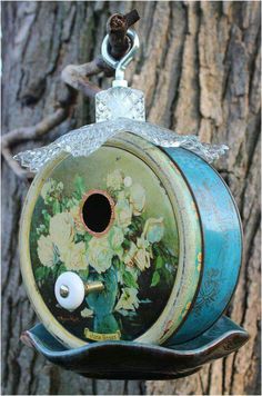 a birdhouse with flowers painted on it's side hanging from a tree branch