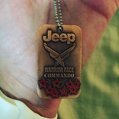 a hand holding a brown jeep tag with red stars on it and the words jeep warrior race commander