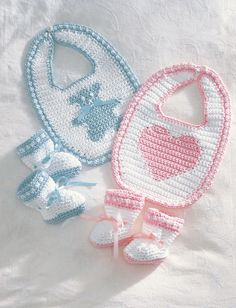 two crocheted baby bibs and booties on a white sheet