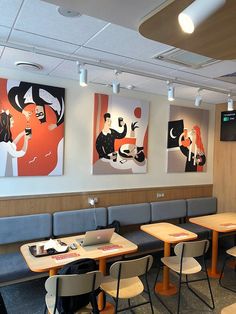 an empty restaurant with three paintings on the wall