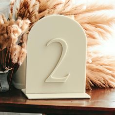 the number two is next to a vase with dry grass in it on a table