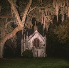 an old church with moss hanging from the trees