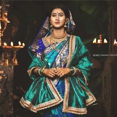 a woman in a blue and green sari is posing for the camera with candles behind her