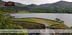 an aerial view of a large lake with mountains in the background and a walkway leading up to it