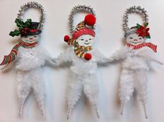 three snowmen are hanging from the wall with christmas decorations on their heads and arms