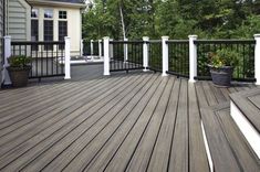 a deck with potted plants and grill on it