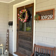 a wooden bench sitting in front of a door with a wreath on it's side