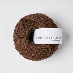 a skein of brown yarn sitting on top of a white table next to a tag