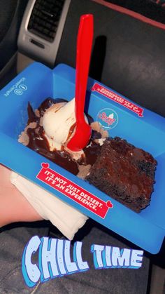 a person holding a blue tray filled with brownies and ice cream on top of it