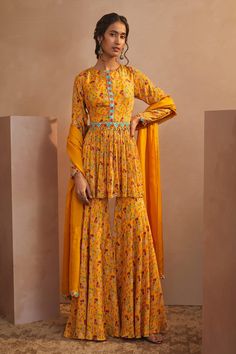 Yellow peplum style kurta with floral printed motifs and mirror embroidery. Comes with sharara, belt and dupatta.
Component: 4
Pattern: Print and Embroidery
Type Of Work: Floral Print, Mirror and Thread
Neckline: Round
Sleeve Type: Full
Fabric: Chinon Chiffon
Color: Yellow
Other Details: 
Dupatta with embroidered border
Closure: Hook front
Occasion: Sangeet - Aza Fashions Peplum Sharara, Yellow Sharara, Yellow Floral Print Dress, Mango Yellow, Haldi Outfits, Sharara Pants, Kurta Sharara Set, Indian Designs, Floral Dress Design