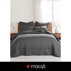 a bed in a bedroom next to a window with the words macy's written on it