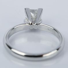 a white gold engagement ring with a single stone in the center, on a plain surface