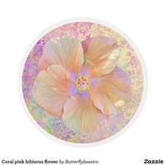 a white and pink flower on top of a glass plate with pastel paint splattered around it