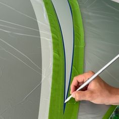 a person is painting the side of a green and white surfboard