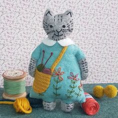 the cat is wearing a blue dress and holding a yarn ball in it's paws