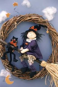 a scarecrow doll sitting on top of a wicker wreath with two black cats