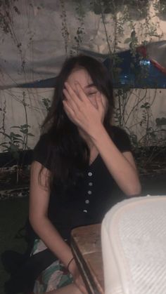 a woman covering her face while sitting at a table