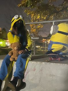 a man sitting on top of a skateboard ramp next to a yellow stuffed animal