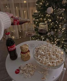 a table topped with a bowl of popcorn next to a christmas tree