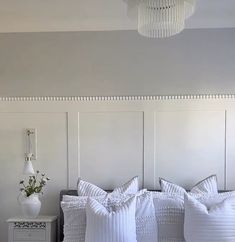 a bed with white pillows on top of it and a chandelier hanging from the ceiling