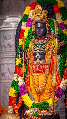 a statue of the hindu god maha in front of a floral display at a temple