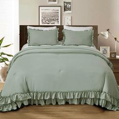 a bed with green ruffles and pillows in front of pictures on the wall