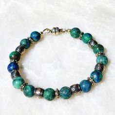 Vivid blue-green Chrysocolla beads are eye-catching and unique, and accented with complementary silver-plated spacer beads for this 7 1/4-inch bracelet, which closes with an easy and convenient magnetic clasp. The bracelet will be packaged in a jewelry gift box with an organza gift bag.  Please measure your wrist carefully to insure a proper fit.    Chrysocolla, sometimes mistaken for turquoise, is a beautiful, vivid blue-green color. Said to be a calming stone with healing power, it's also associated with wisdom and peace. In ancient Egypt, it was known as a wisdom stone, beneficial in negotiations because those who wore it reached compromise and resolution.  More recently it has become a favored stone for jewelry symbolizing luck and prosperity.* * Please note that the information I prov Calming Stones, Natural Stone Jewelry, Magnetic Clasp, Healing Powers, Organza Gift Bags, Jewelry Gift Box, Spacer Beads, Stone Jewelry, Natural Stones