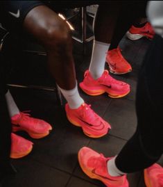 the legs and feet of several people in pink shoes, all wearing white socks with neon orange soles