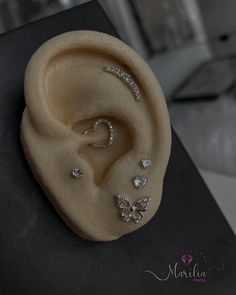 a close up of an ear with some jewelry on it's side and a black box in the background