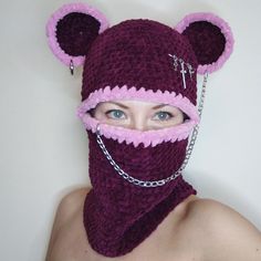 a woman wearing a knitted bear mask with chains around her neck