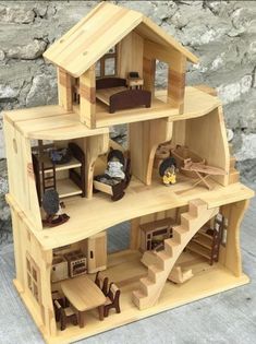 a wooden dollhouse with stairs and furniture on the top floor next to a stone wall